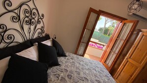 Une chambre à coucher avec un lit, une armoire en bois et une vue sur l’extérieur par une porte ouverte.