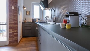 A modern kitchen with a brick accent wall, a built-in microwave, a gas stove, and a large window. - Casa Andreis by Wonderful Italy (Turin)