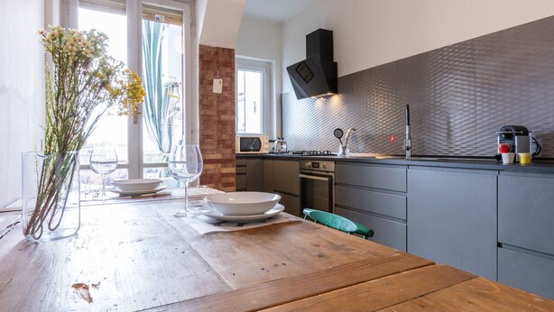 A modern kitchen with grey cabinets, a wooden table, and a window with curtains. - Casa Andreis by Wonderful Italy (Turin)