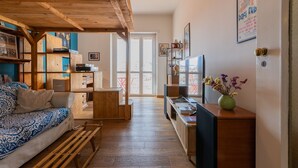 A cozy living room with a wooden ceiling, a sofa, a coffee table, and a TV stand. - Casa Andreis by Wonderful Italy (Turin)