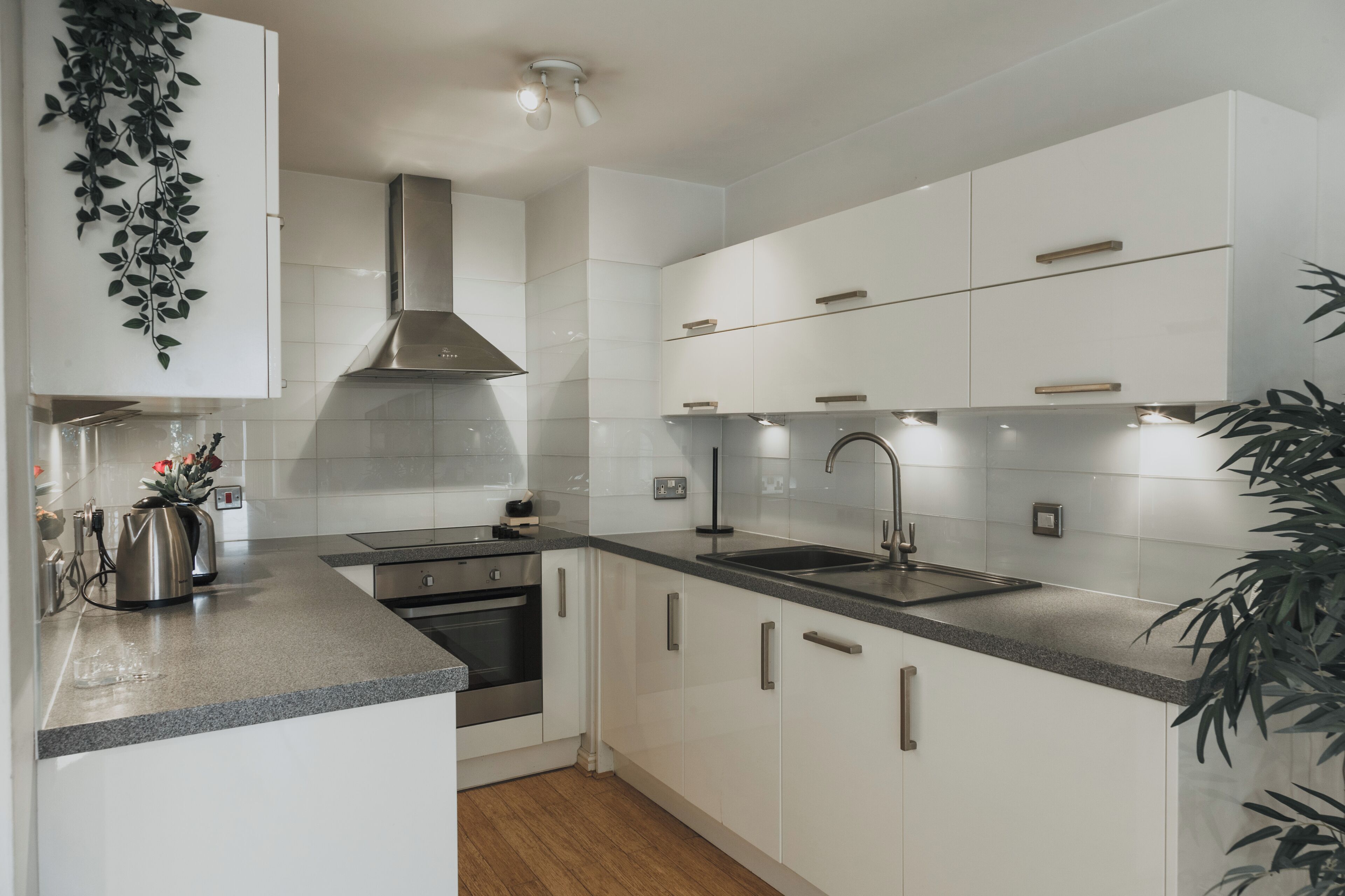 A modern kitchen with white cabinetry, stainless steel appliances, and a granite countertop.