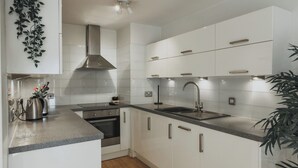 A modern kitchen with white cabinetry, stainless steel appliances, and a granite countertop.