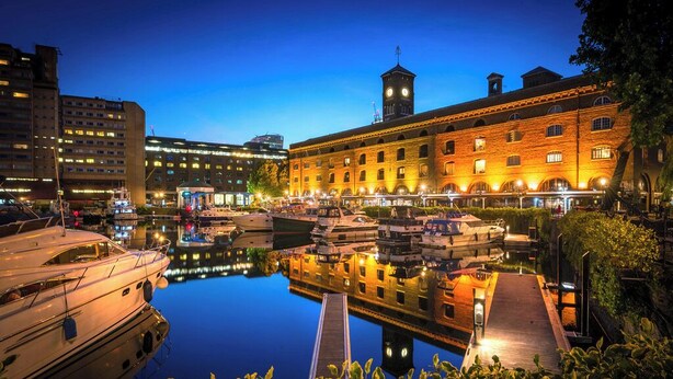 A marina with boats docked, a wooden dock, and a building with a clock tower.