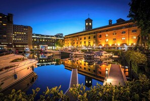 A marina with boats docked, a wooden dock, and a building with a clock tower.
