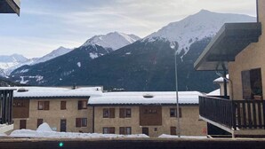 Un bâtiment doté de nombreuses fenêtres et d’un toit recouvert de neige, se dressant sur fond de montagnes enneigées.