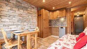 A cozy room with a stone wall, wooden furniture, a tiled backsplash, and a bed with red pillows.