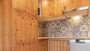 A kitchen with wooden cabinets, a patterned backsplash, and a dishwasher.
