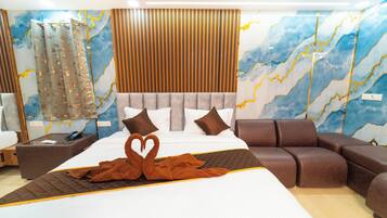 A modern hotel room with a large bed, a brown sofa, and a decorative swan towel arrangement.