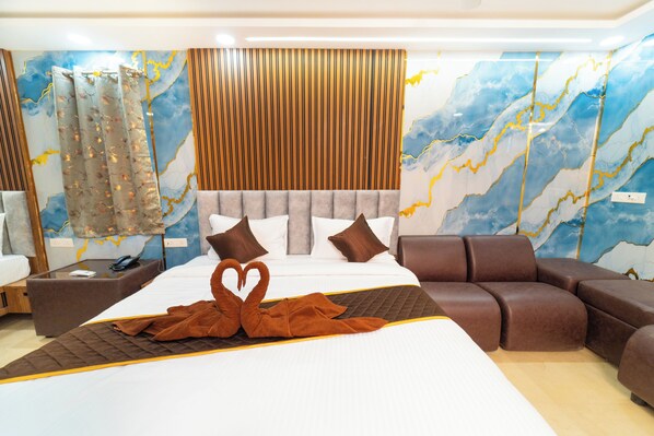 Een moderne hotelkamer met een groot bed, een bruine bank en een decoratieve handdoekopstelling in de vorm van een zwaan.