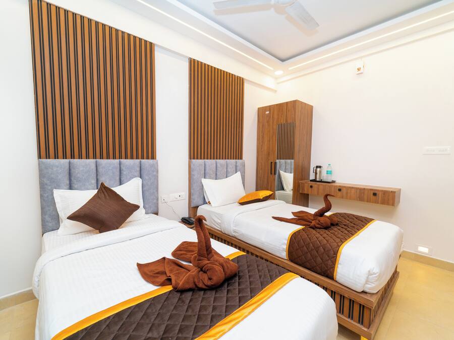Habitación de hotel con dos camas, cabeceros de madera, un tocador con espejo y un ventilador de techo.