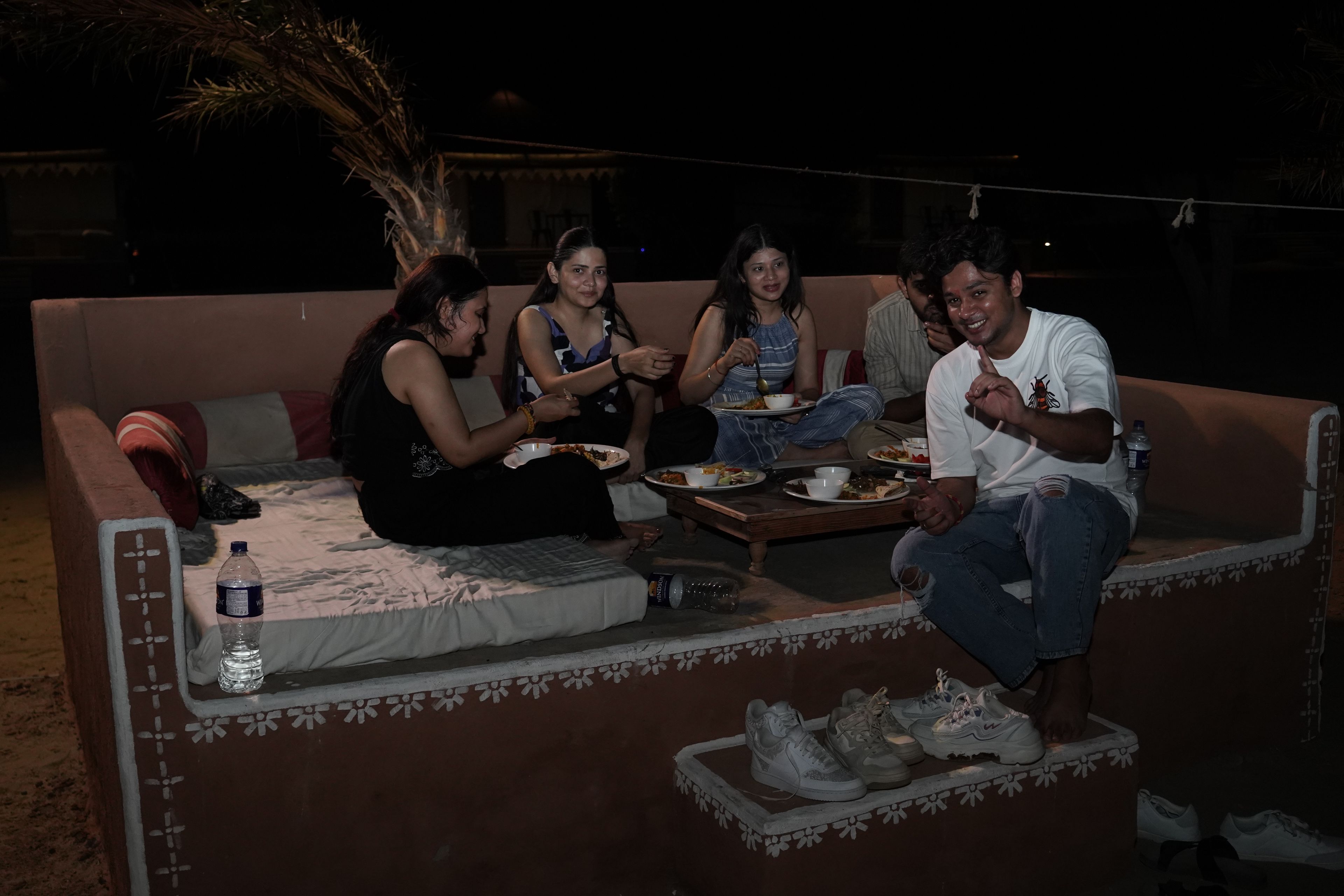 A group of people sitting on a sofa with a table in front of them, eating.