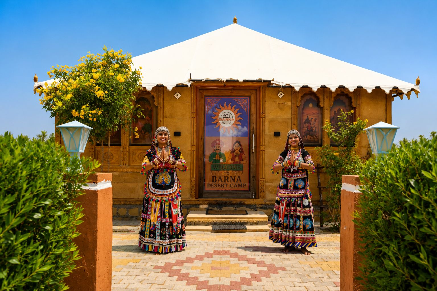 Two individuals in traditional attire standing in front of a building with a sign that reads 'Barna Desert Camp.'