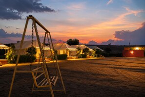 A campsite with tents, a swing set, and a dirt ground. - barna dersert camp jaisalmer (Jaisalmer)