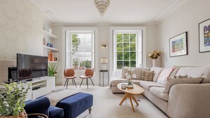 A living room with a television, two chairs, a sofa, a coffee table, and a chandelier.