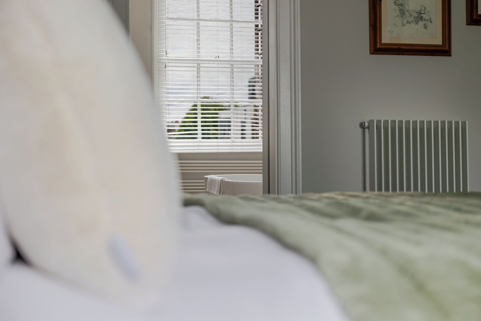 Un dormitorio con cama, radiador y ventana con persianas.