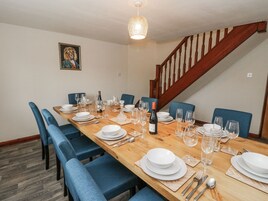 Comedor con una mesa de madera dispuesta para una comida, sillas tapizadas en azul y una araña.