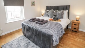 Une chambre bien rangée, avec un lit, des tables de chevet, une lampe de chevet, un plateau avec des éléments pour le petit-déjeuner et une fenêtre donnant sur un beau paysage.