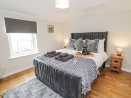 Un dormitorio ordenado con cama, mesitas de noche, lámpara de noche, una bandeja con alimentos para el desayuno y una ventana con vistas.