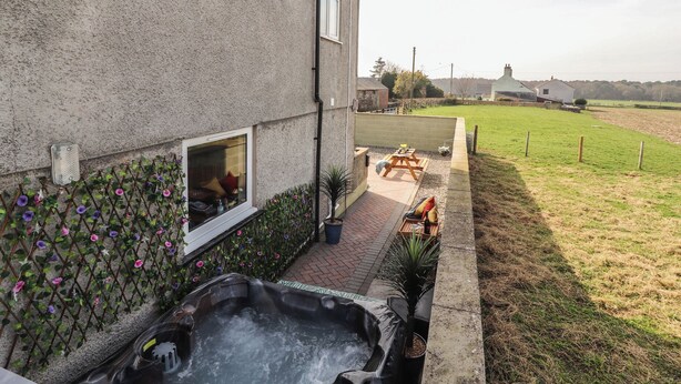 Une maison avec un patio, un jacuzzi et une cour clôturée.