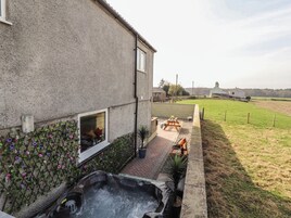 Una casa con patio, jacuzzi y jardín cercado.