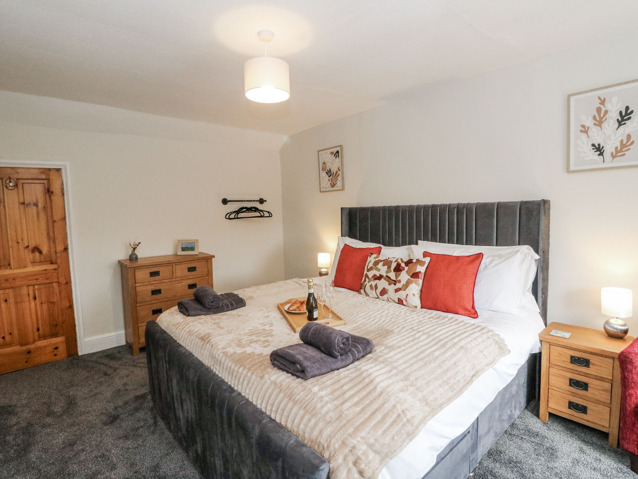 Un dormitorio con cama, cómoda de madera y mesita de noche.