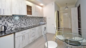 A modern kitchen with grey and white cabinetry, a checkered backsplash, a built-in washing machine, and a glass table with chairs. - Mashtots  apartment by Luxe Group MA154 (Yerevan)