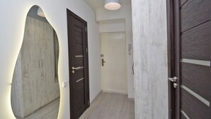 A hallway with a modern design, featuring a curved wall, a wooden door with a handle, and a white ceiling light. - Mashtots  apartment by Luxe Group MA154 (Yerevan)