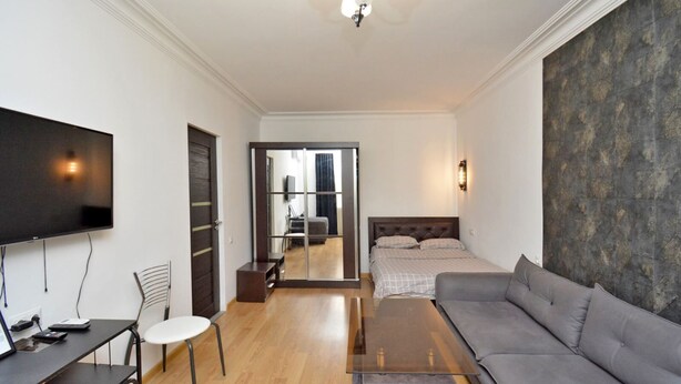 A modern living room with a sofa, a TV, a desk, and a chair. - Mashtots  apartment by Luxe Group MA154 (Yerevan)