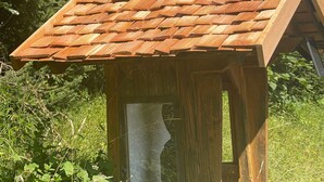 Une structure en bois dotée d’un toit en pente, entourée de verdure.