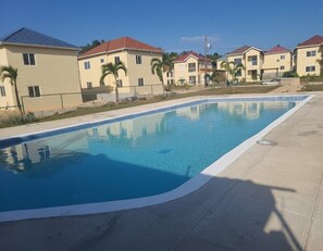 Una piscina con borde de azulejos, rodeada por una terraza de concreto.