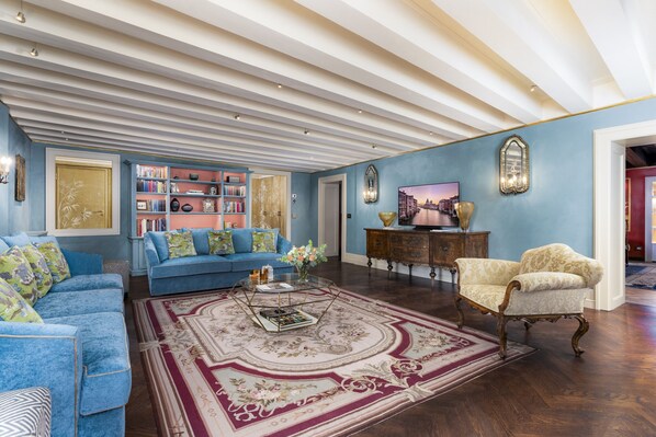 Un salón amplio con un sofá azul, un tapete estampado y un mueble de madera.