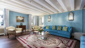 Un salon spacieux avec un canapé bleu, deux fauteuils, une table basse et un tapis à motifs.