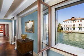 Una habitación con un gran ventanal que da a un canal, un armario de madera y un cuadro en la pared.