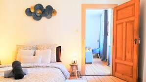 Un dormitorio con una cama, una mesita de noche, una lámpara, una alfombra mullida y una puerta de madera que da a un balcón.