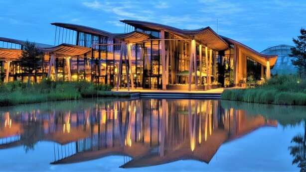 Un edificio moderno con grandes ventanales y un reflejo en el agua.