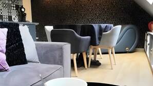 A modern living room with a sofa, dining table, chairs, and a coffee table with decorative mugs.