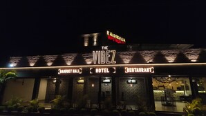 En byggnad med en skylt som visar texten ”The Vibez” och ”Kaidikhan Restaurant”. Den har en fasad av tegel och en balkong.