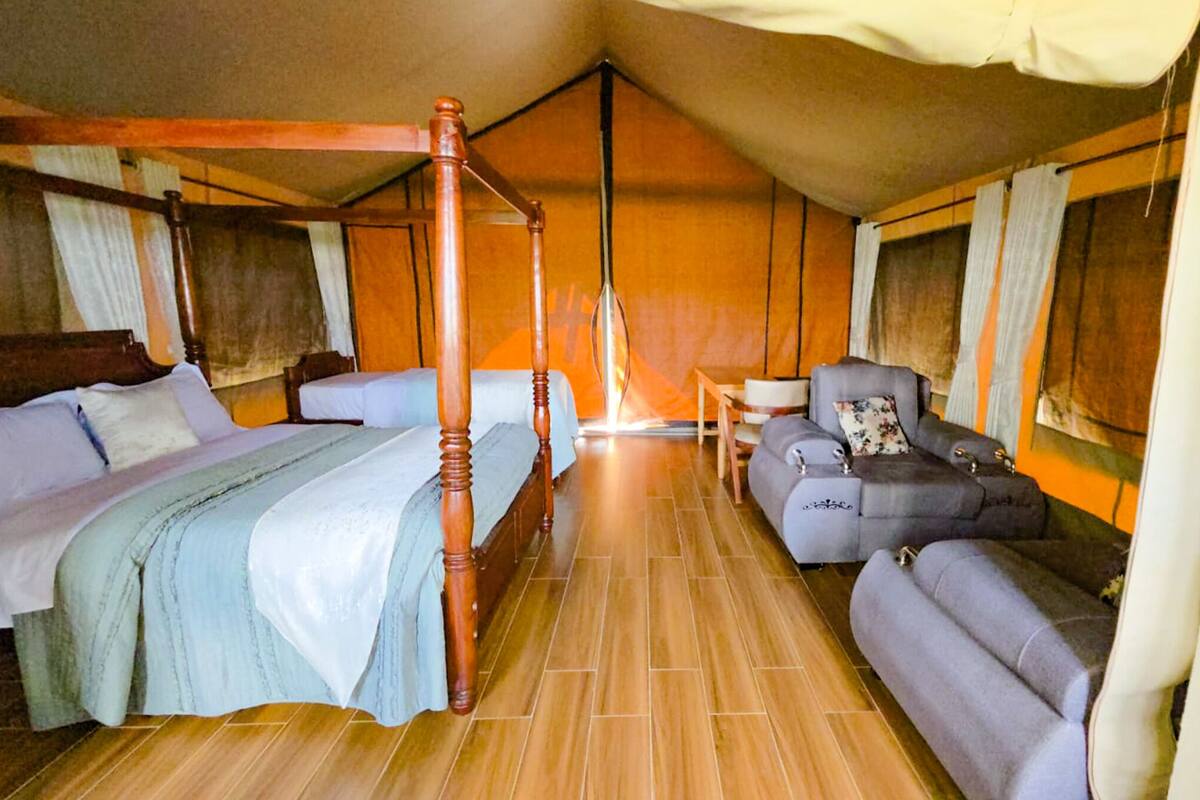 Una habitación con una cama con dosel, un sofá y una mesita.