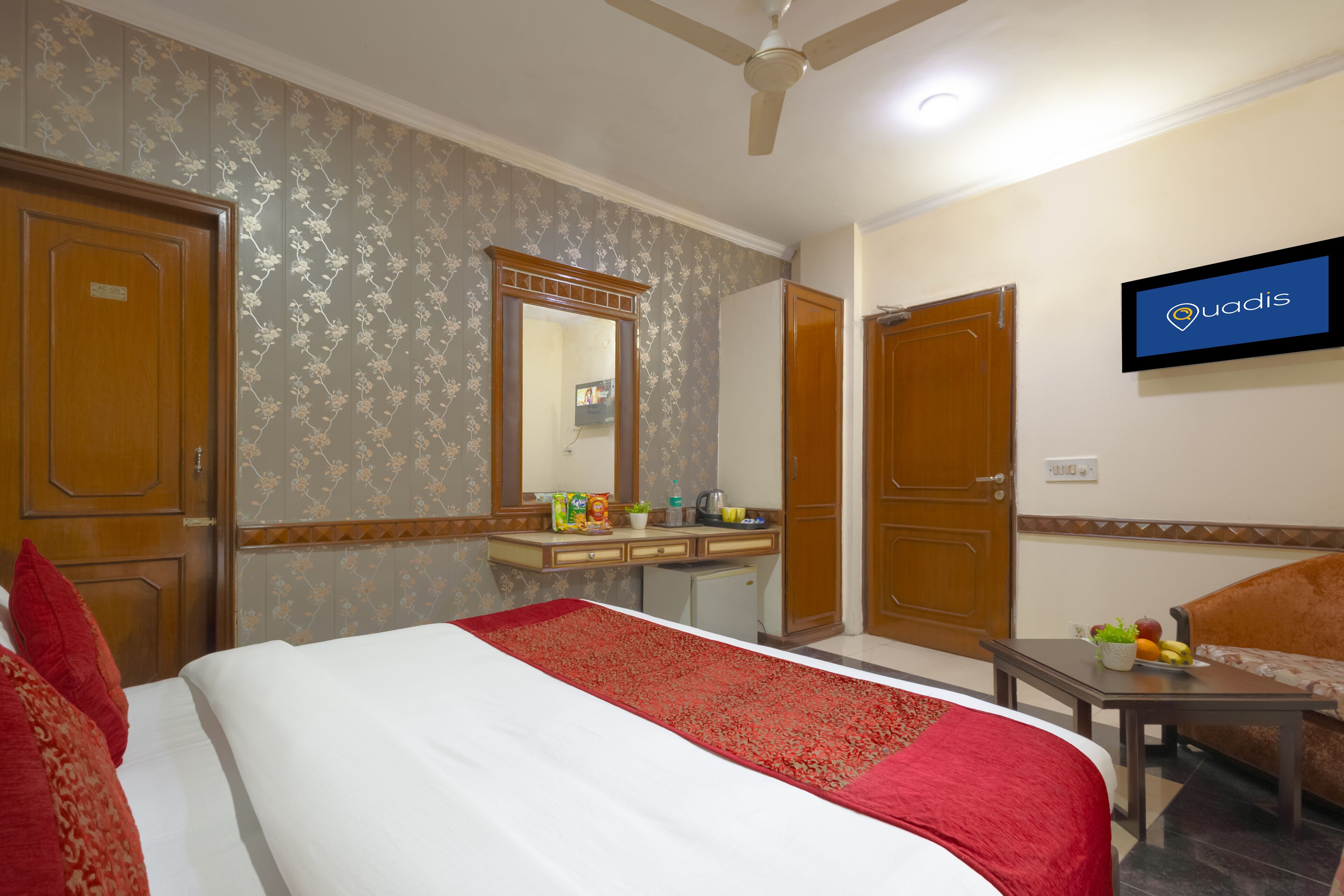 A hotel room with a bed, a desk, a chair, a television, and a wardrobe.