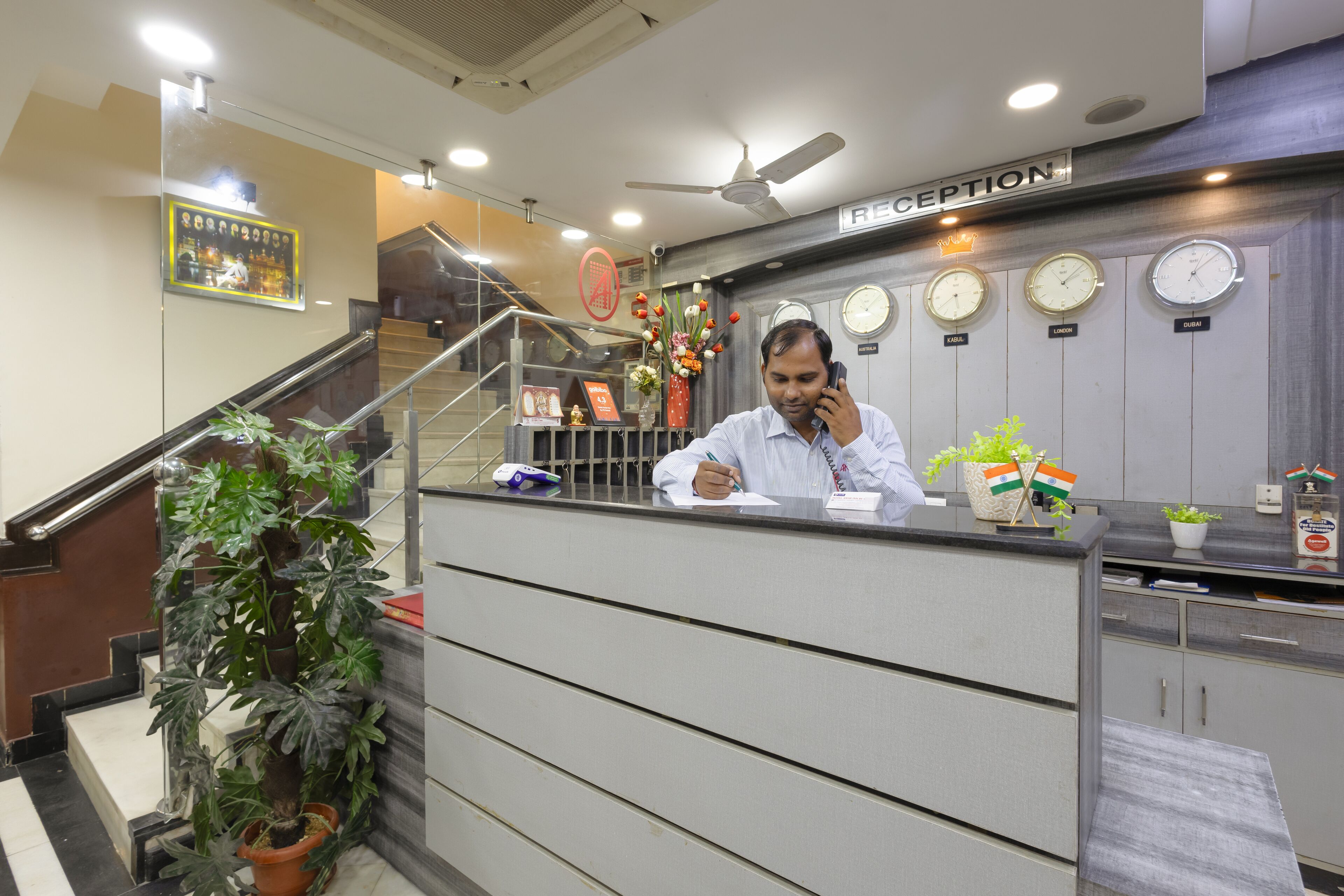 A reception desk with clocks, a reception sign, and a staircase.