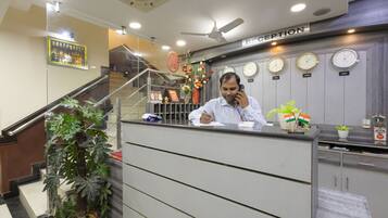A reception desk with clocks, a reception sign, and a staircase.
