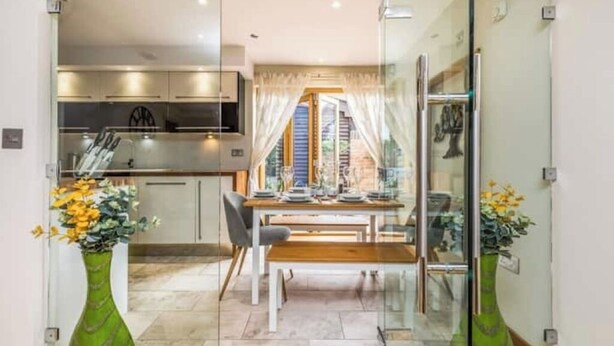 A modern kitchen with a dining area, a glass partition, and a view of the outside.
