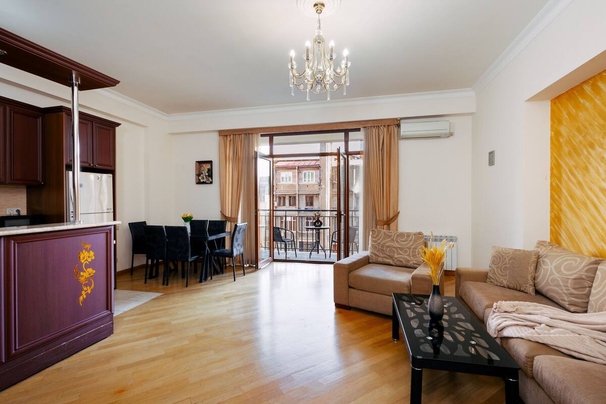 A modern living room with a sofa, a coffee table, and a dining area with chairs and a table.