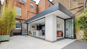 Una cocina moderna con comedor, ventanas grandes y vistas al jardín.