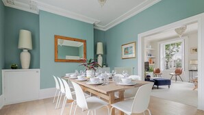 Comedor con una mesa de madera dispuesta para seis personas, rodeado de sillas blancas.