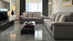 A modern living room with two sofas, a coffee table, a TV, and a lamp.
