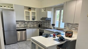 A modern kitchen with stainless steel appliances, a tiled backsplash, and a breakfast bar with stools.