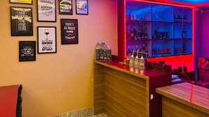 A bar area with a neon sign, a counter with bottles, and framed quotes on the wall. - Hotel Ronak  By Red Panda (Gangtok)