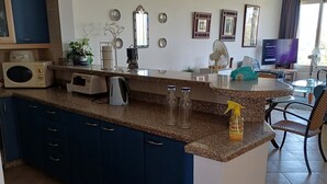 A modern kitchen with blue cabinets, a granite countertop, and a built-in microwave.