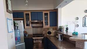 A compact kitchen with blue cabinets, a stove, a microwave, and a refrigerator.